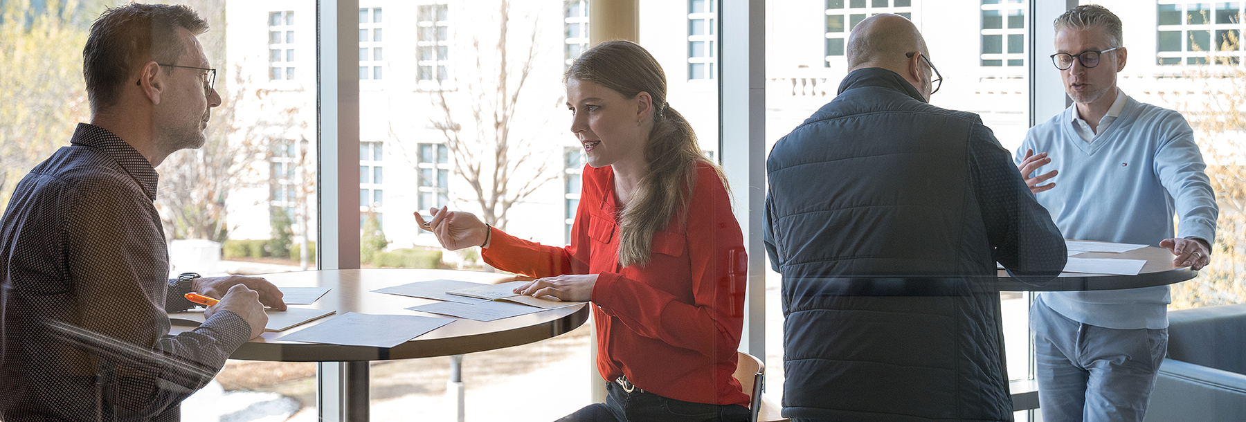 Section Image: Executives standing at tall tables with papers discussing 
