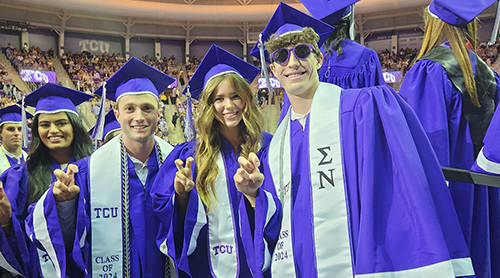 Section Image: Graduates take pictures in cap and gown with family outside of Schollmaier Arena 